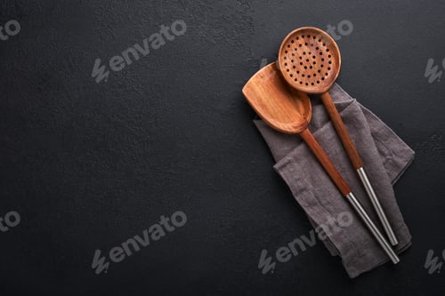 Preview: Cooking wooden utensils, basil leaves and spices on dark stone background. Abstract food background.