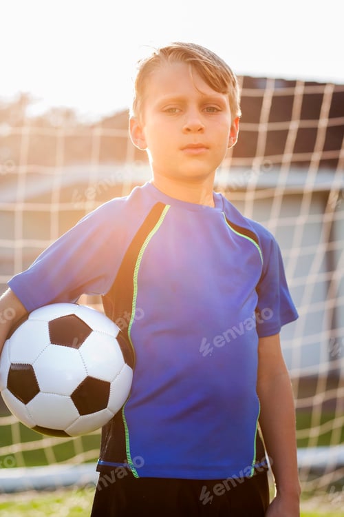 Preview: Portrait of boy football player holding football in front of goal