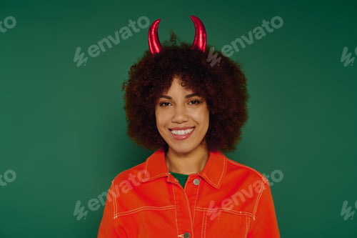 Preview: Young woman with curly hair expresses joy against a vibrant green background in casual style