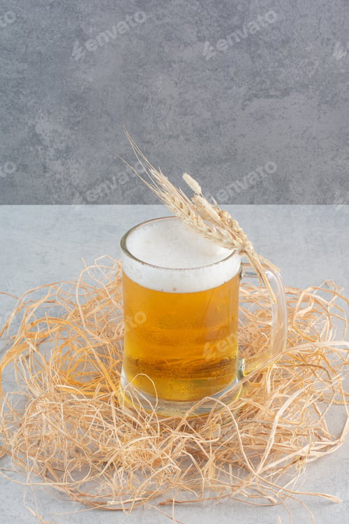Preview: A glass of delicious beer with wheat on hay background
