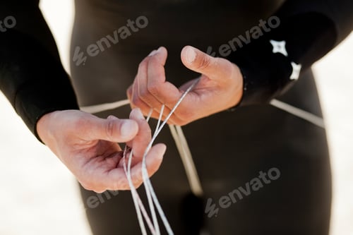 Preview: Midsection of man in wetsuit holding strings