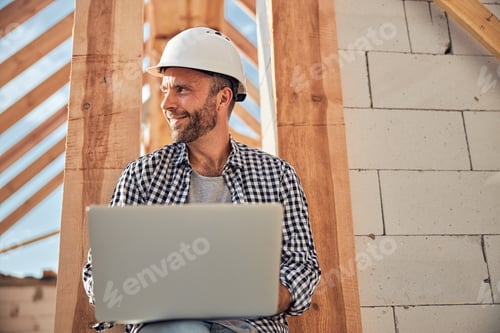 Preview: Cheerful young architect using his laptop outdoors