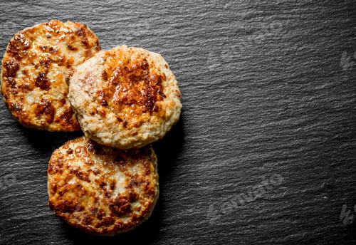 Three Freshly Cooked Burger Patties on Black Slate