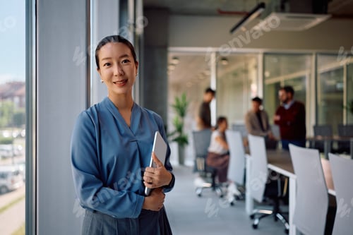 Preview: Portrait of smiling Korean businesswoman in the office looking at camera.