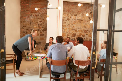 Preview: Young woman addressing a team meeting in a boardroom
