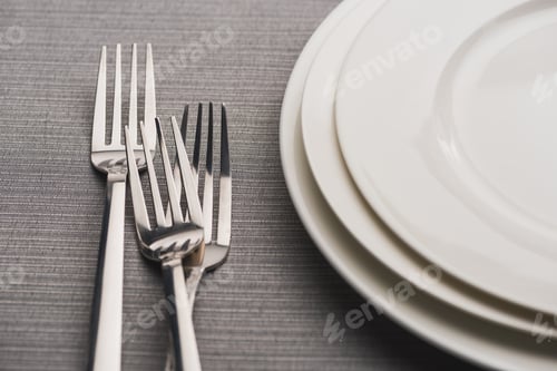 Preview: Empty plates with forks on grey linen tablecloth