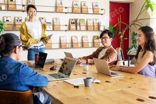 Preview: Group of young Japanese professionals working on laptop computers in a co-working space.