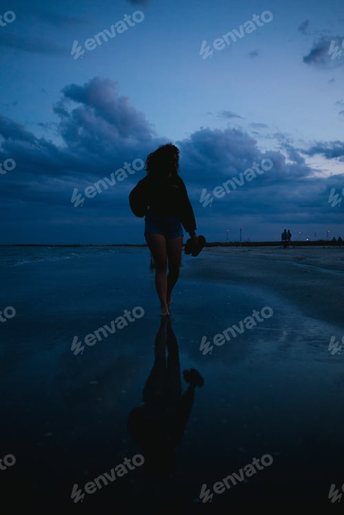 Preview: Woman walking bare feet on the beach in the sunset