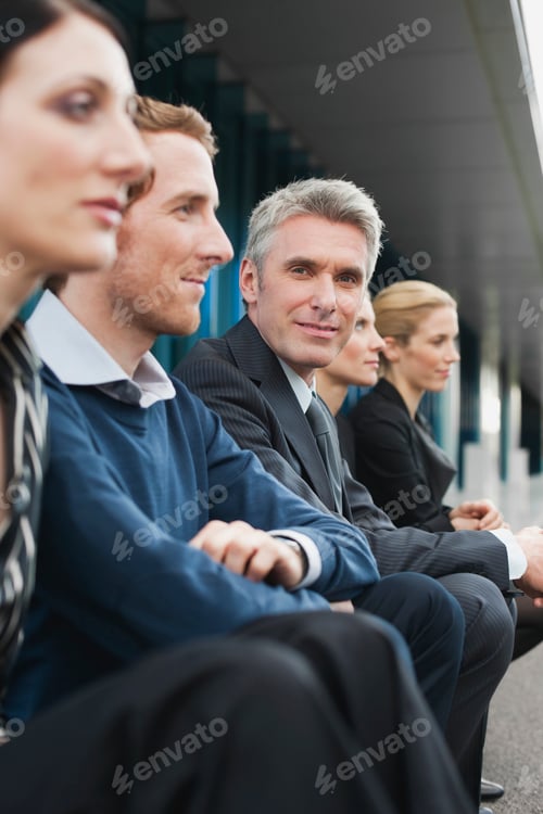 Preview: Germany, Hamburg, Four Business people sitting on steps in front of office building