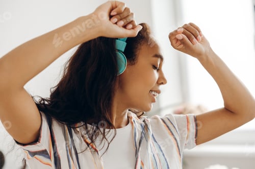 Preview: Happy, smiling African American woman listening music dancing enjoying in living room at home
