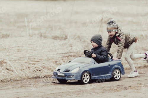 Preview: Two happy kids having fun drive a blue toy car, road trip adventure concept