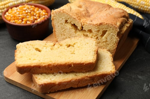 Preview: Freshly baked cornbread, cobs and seeds on black table, closeup