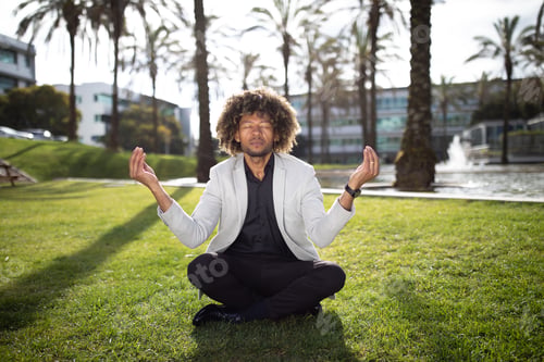 Preview: Stress relief concept. Calm black middle aged businessman meditating outdoors, practicing yoga