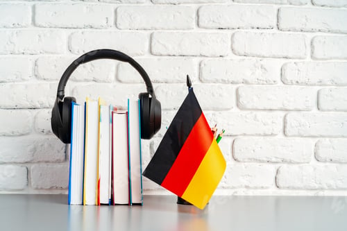 Preview: Stack of books and flag of Germany on desk. German language learning concept