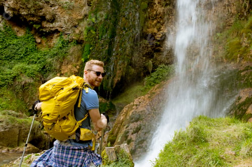 Preview: Young hiker stopped beside a mountain waterfall to rest