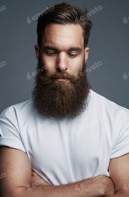 Preview: Bearded young man standing thoughtfully with his arms crossed