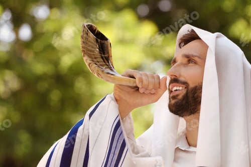Preview: Jewish man in tallit blowing shofar outdoors. Rosh Hashanah celebration