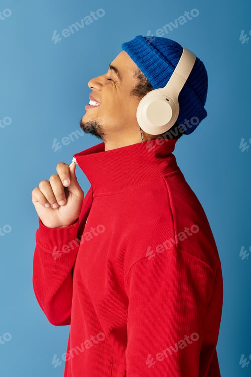 Preview: Stylish young African American man enjoys music against a vibrant blue background