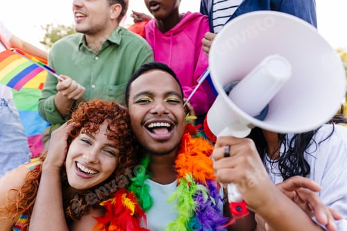 Preview: Happy gay couple smiling with rainbow flag and megaphone at pride parade