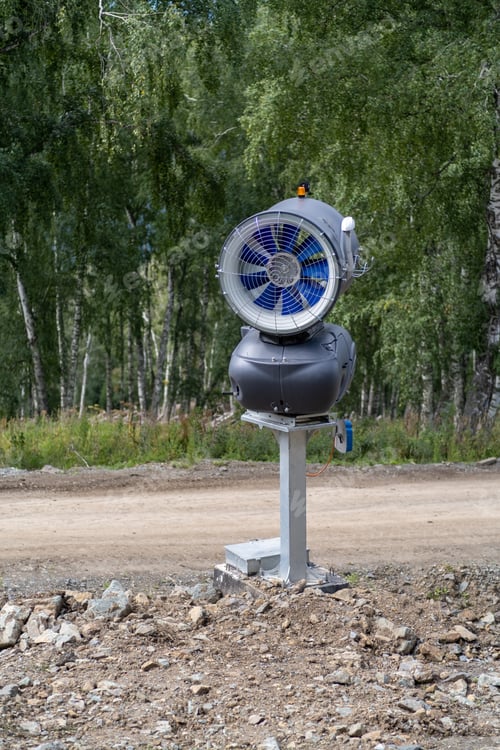 Preview: Yellow snow cannon on the edge of a hill overlooking valley in summer