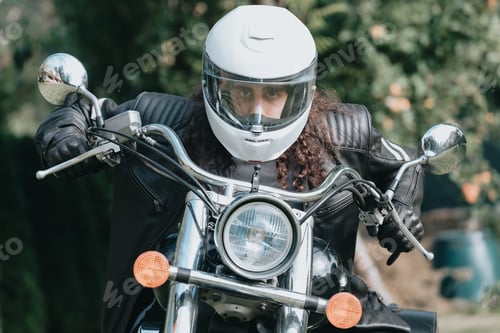 Preview: Portrait of a young long hair man, an old biker in a leather jacket on a retro bike,