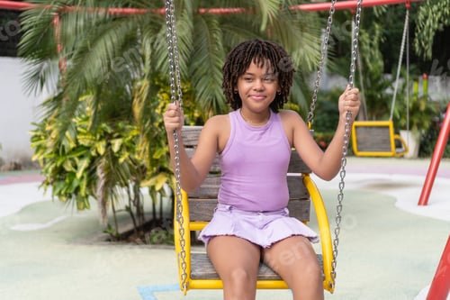 Preview: Happy black girl enjoying swing at playground