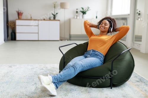 Preview: Calm black woman having rest at home on bean bag