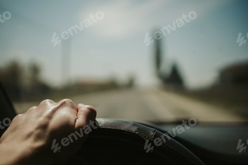 Preview: Closeup shot of a person driving a car while holding the steering wheel