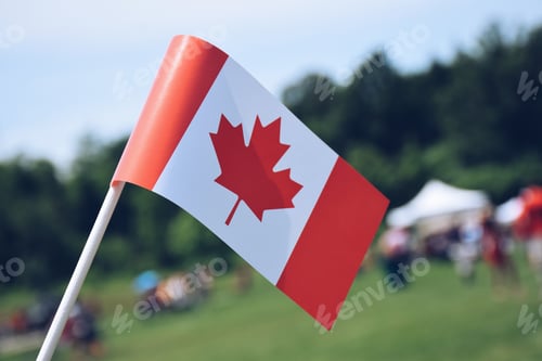 Preview: A Canadian flag with blurred fairgrounds in the background