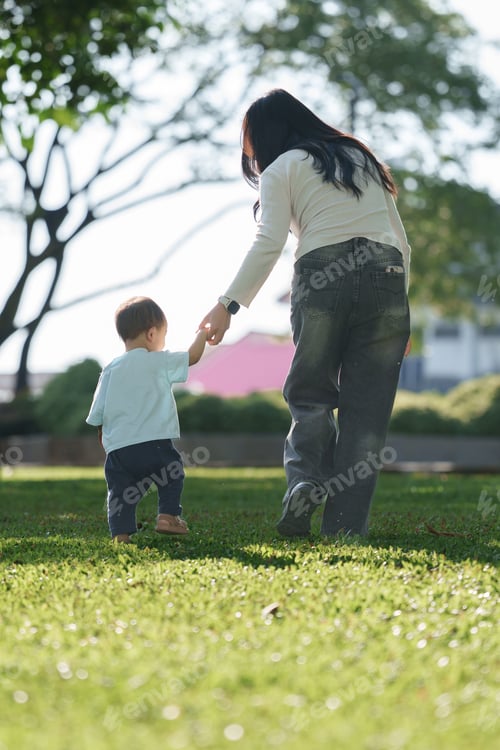 Preview: Mother holding baby hand walking in park