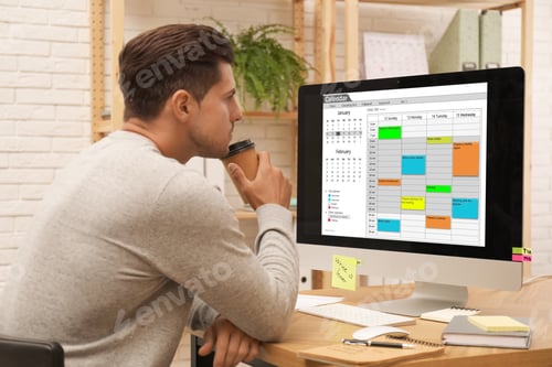 Preview: Handsome man using calendar app on computer in office
