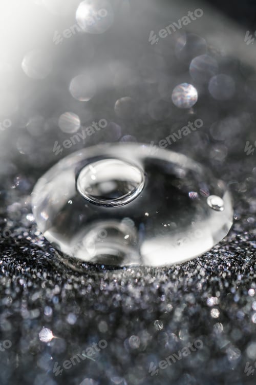 Preview: A drop of cosmetic gel on a black shining background.