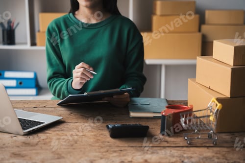 Preview: Small business entrepreneur SME owner checking customer details on packaging box preparing for deliv
