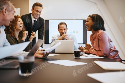 Preview: Diverse work colleagues laughing together during a boardroom meeting