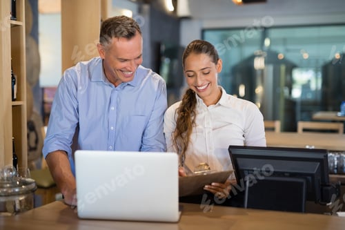 Preview: Manager and bartender discussing over clipboard in bar