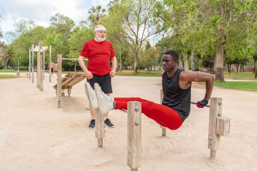 Preview: Side view of muscular young African American male athlete working out on parallel on sports ground