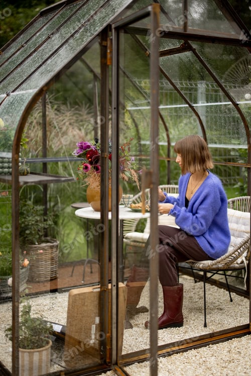 Preview: Woman relaxing in glasshouse in garden