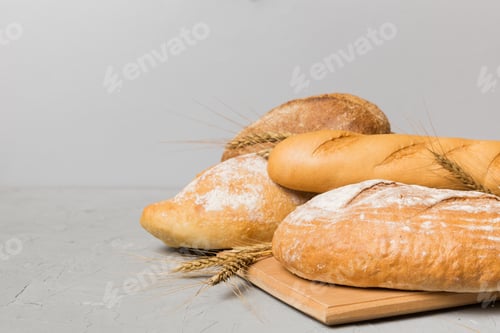 Preview: Freshly baked bread on cutting board against white wooden background.