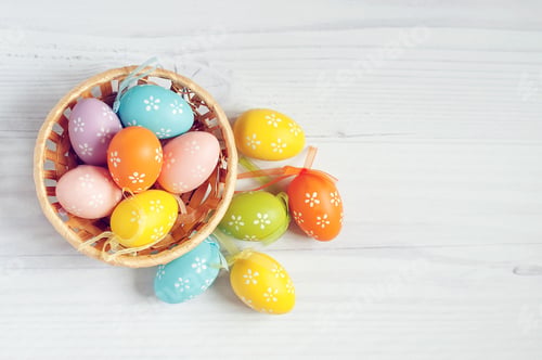 Preview: Easter Eggs in nest. Basket of colorful easter eggs on wooden table with free copy space