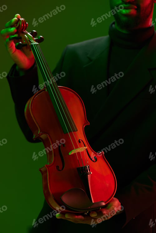 Preview: Classically Dressed Man Holding Violin Against Vibrant Green and Red Background on Photo Banks