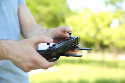 Preview: Man holding new modern drone controller outdoors, closeup of hands