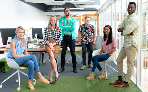 Preview: Front view of diverse business people looking at camera in a modern office