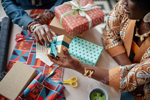 Preview: Black Woman and Black Man Exchanging Wrapped Gifts during Kwanzaa Celebration