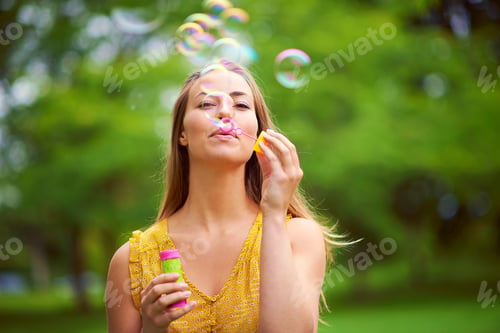Preview: Indulging her inner child. Shot of a carefree young woman blowing bubbles in the park.