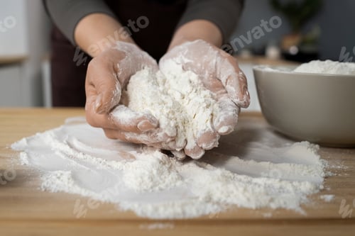 Preview: Hands of young female holding pile of sifted flour