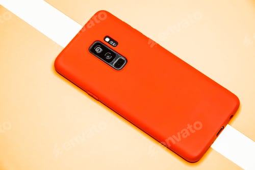 Preview: Closeup shot of a phone with a red case on an orange background