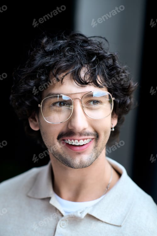 Preview: Young man with curly hair and glasses smiling joyfully in a casual setting