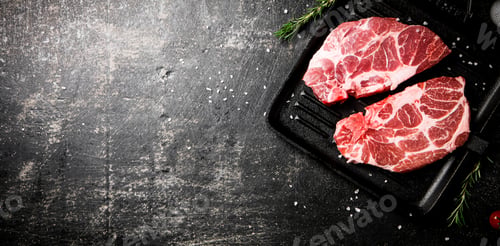 Preview: Raw pork steak on a grill pan.