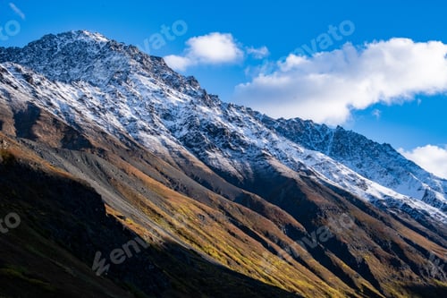 Preview: Majestic mountain range with snow-capped peaks and lush green grass in the foreground