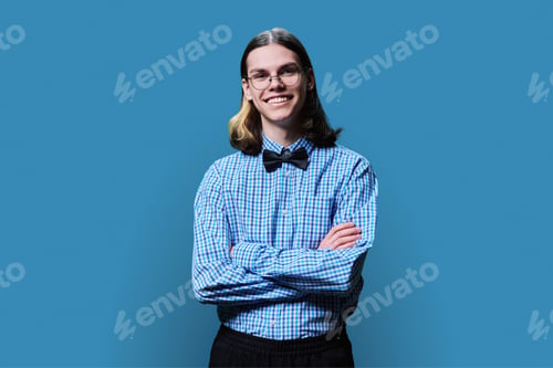 Preview: Confident young male posing with crossed arms against blue background